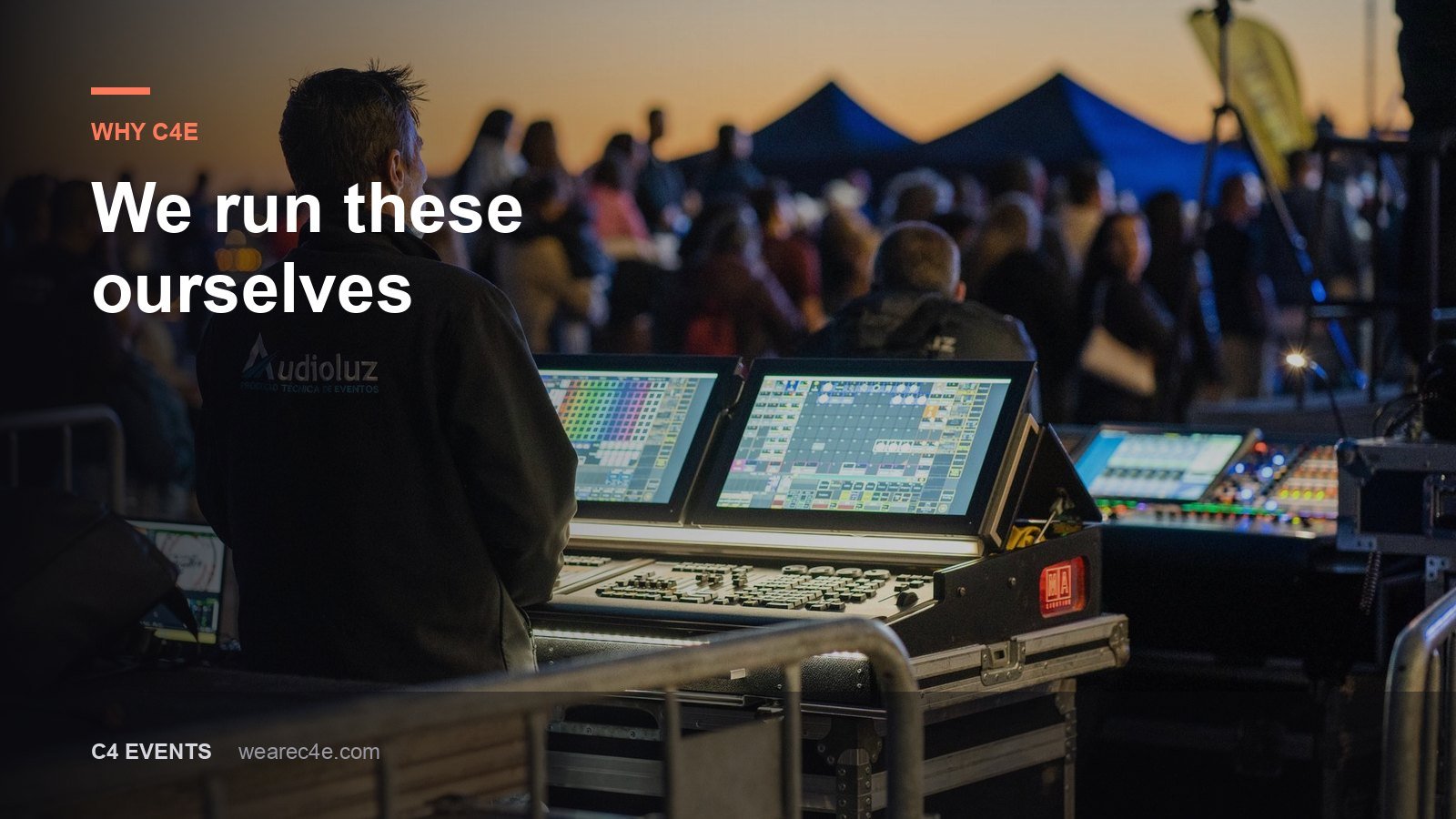 A technician working a lighting and sound desk at the back of a live event.