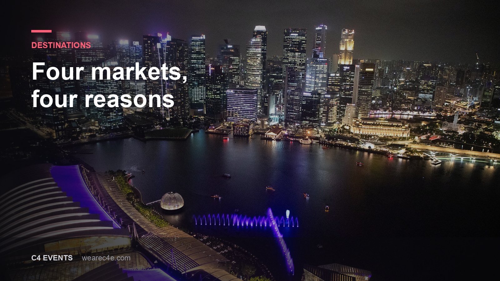 Singapore's Marina Bay skyline lit at night, seen from the air.