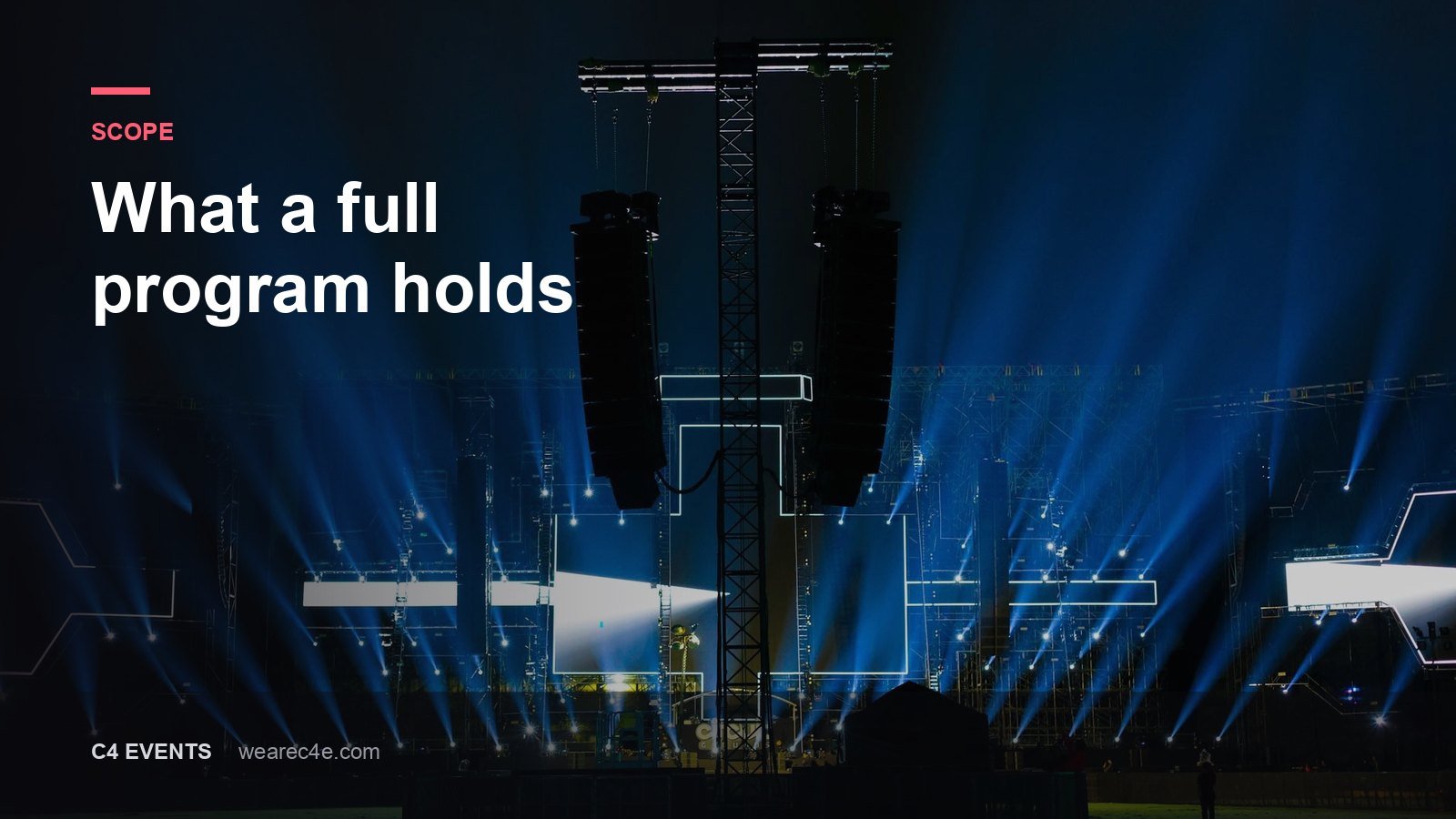 A concert-scale stage with lighting rig and beams cutting across the room.