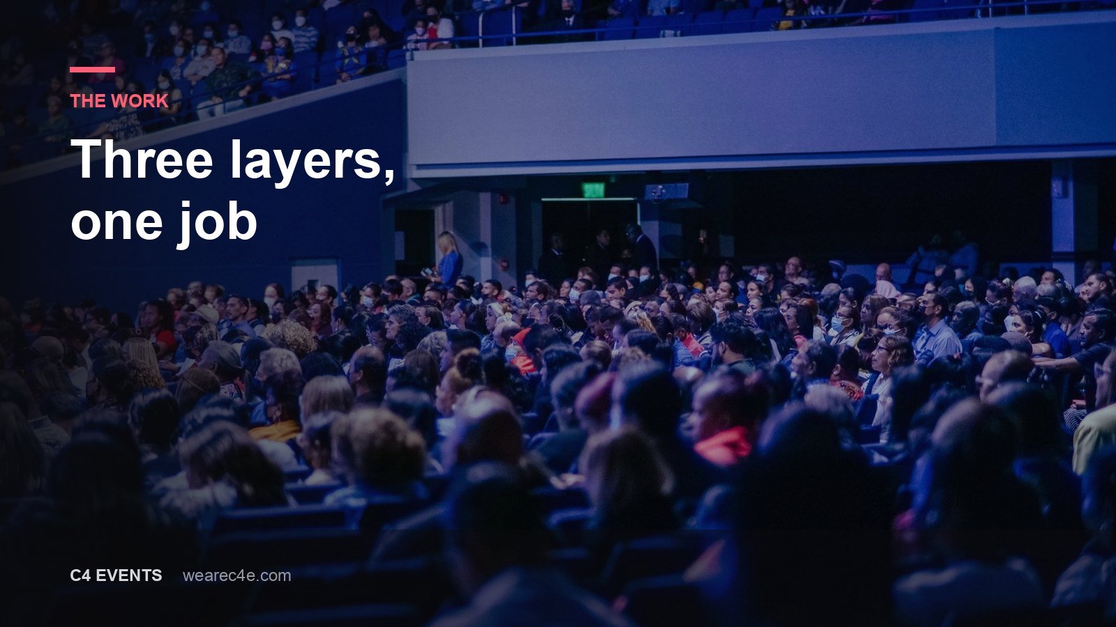 A packed conference auditorium facing a lit stage and a wide screen.