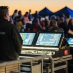 Technician managing sound and lighting panels during an outdoor event at sunset.