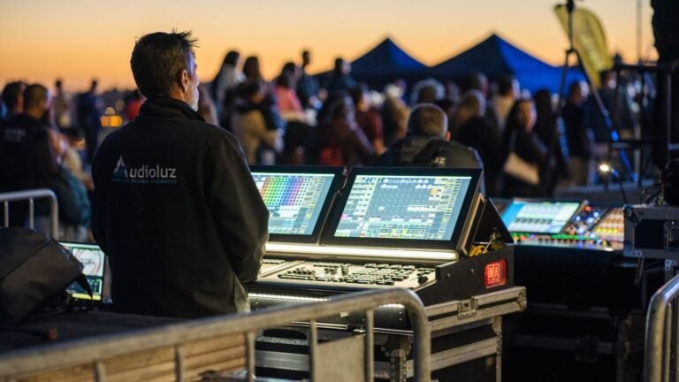 Technician managing sound and lighting panels during an outdoor event at sunset.