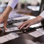 Close-up of hands arranging name tags on a conference table, preparing for a corporate event.