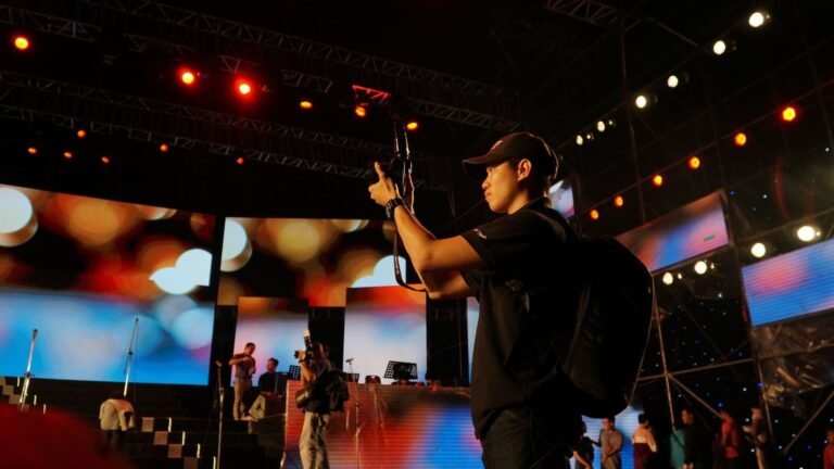 A photographer captures moments at a live music concert with vibrant stage lights.