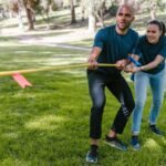 Two adults engaging in a tug of war during a team building event in a park.