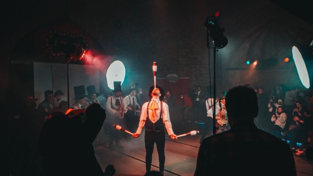 A mesmerizing circus juggler performs under dramatic lighting during a lively festival.