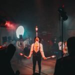 A mesmerizing circus juggler performs under dramatic lighting during a lively festival.